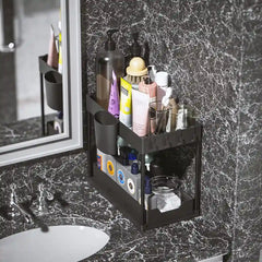 Bathroom counter with a black multi-tiered organizer holding various toiletries against a marble wall.