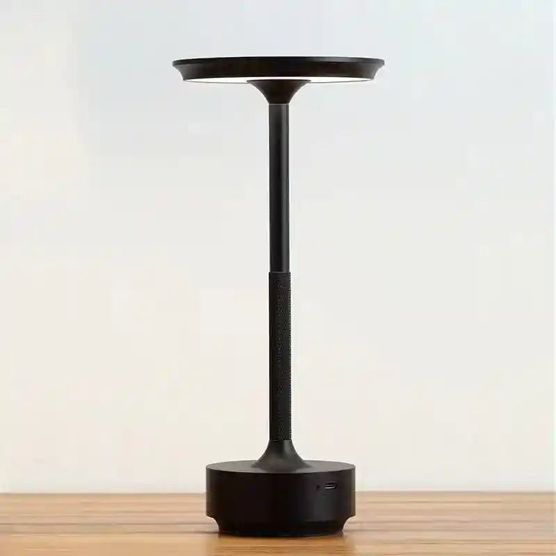 Black portable lamp on a wooden surface with a light background