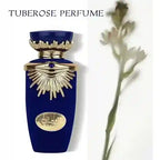 Blue perfume bottle with gold accents and tuberose flower on a white background