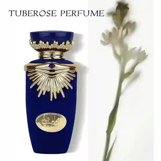 Blue perfume bottle with gold accents and tuberose flower on a white background