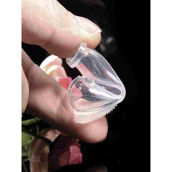 Clear silicone mold shaped like a fish on a finger against a dark background