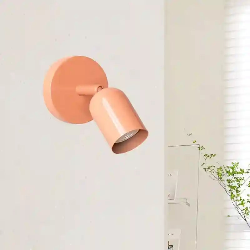 Coral-colored wall-mounted light fixture on a white wall.