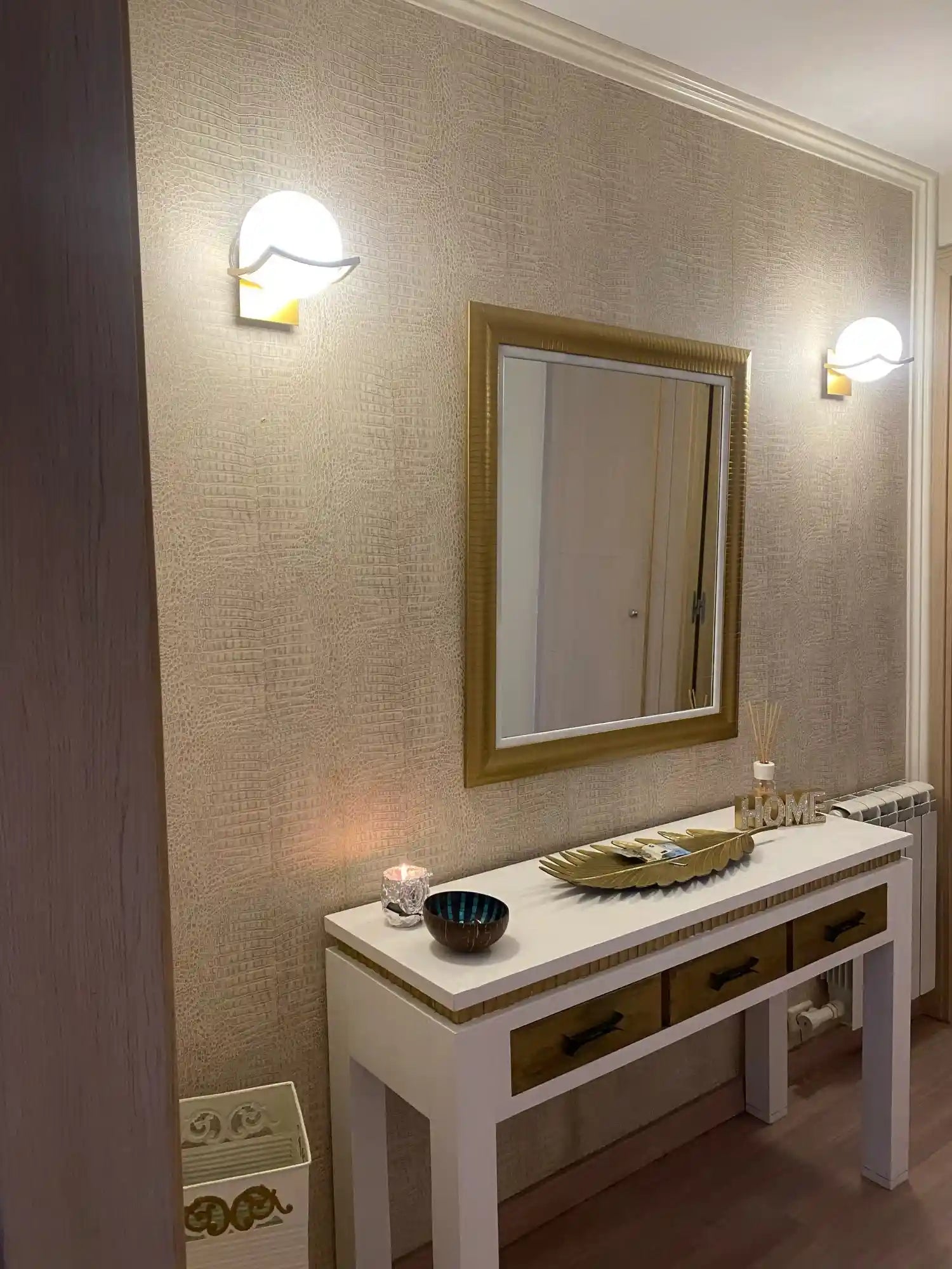 Decorative hallway with a mirror, table, and wall lights.
