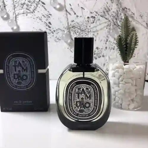 Diptyque Tam Dao perfume bottle and packaging on a white surface with decorative elements.