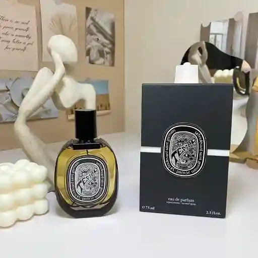 Diptyque perfume bottle and packaging on a table with decorative items.