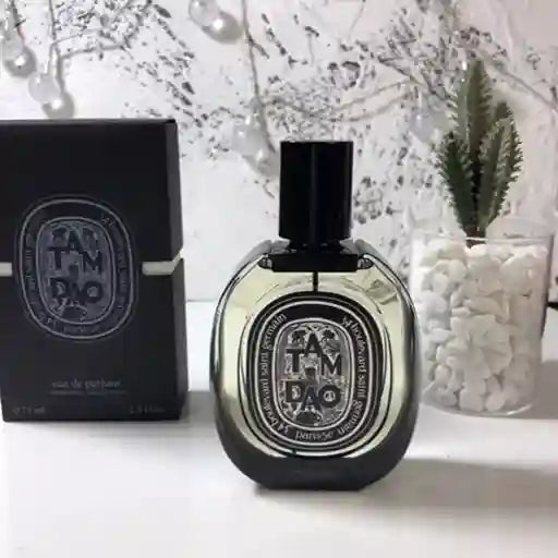 Diptyque perfume bottle and packaging on a white surface with decorative elements.