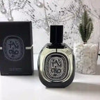 Diptyque perfume bottle and packaging on a white surface with decorative elements.
