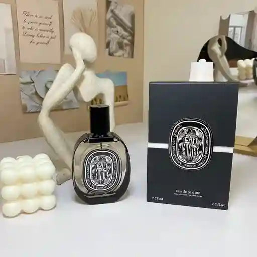 Diptyque perfume bottle and packaging on a table with decorative items.