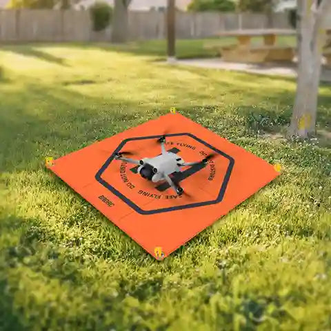 Drone on an orange landing pad with grass and trees in the background