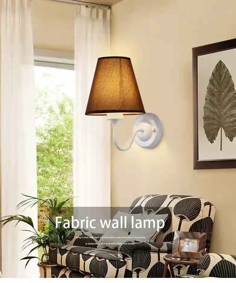 Fabric wall lamp in a living room setting with a sofa and window.