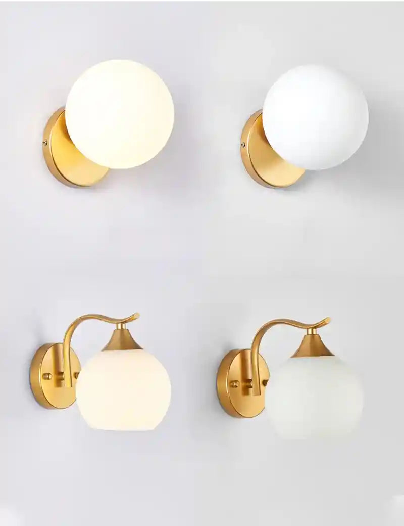 Four gold wall sconces with white glass shades on a light gray background