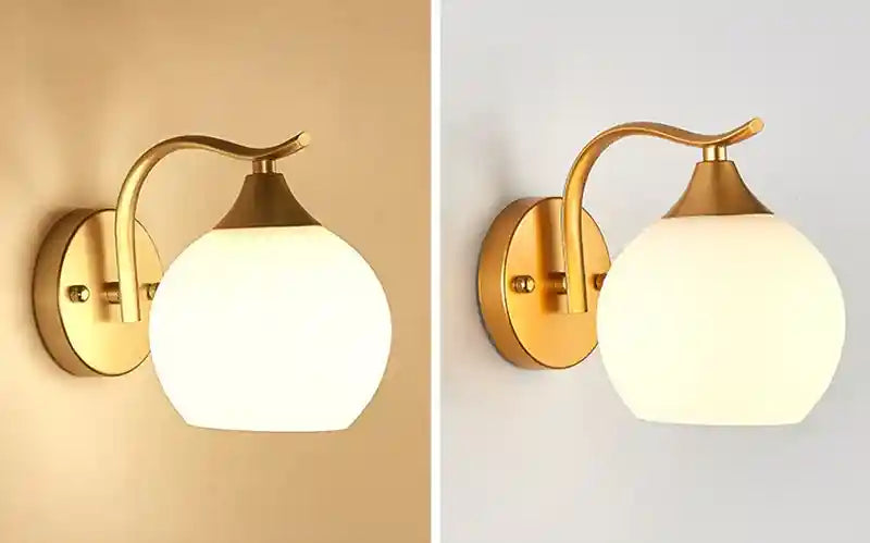 Gold wall sconce with white glass shade on a beige and white background
