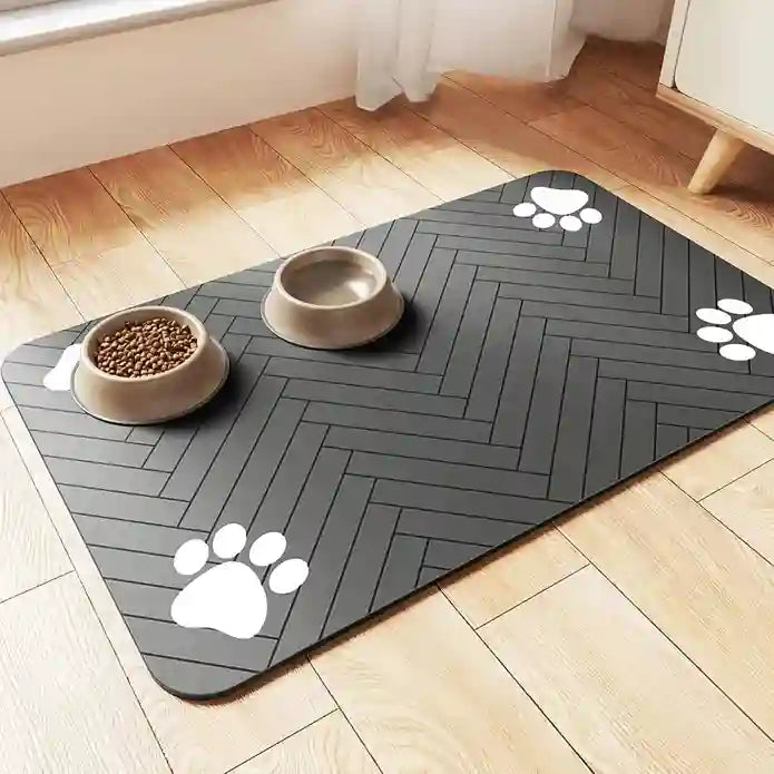 Gray pet mat with herringbone pattern and paw prints on a wooden floor with pet bowls.