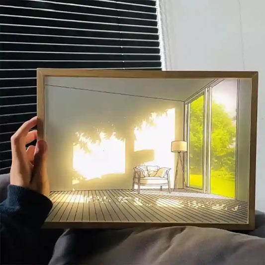 Hand holding a framed picture of a sunlit room with a chair and window.