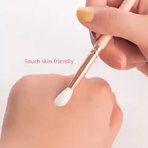 Hand holding a makeup brush with 'Touch skin-friendly' text on a light background