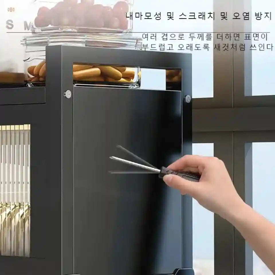 Hand using a tool to open a black cabinet with food items inside.