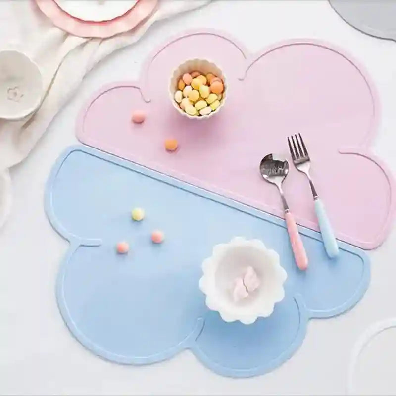 Heart-shaped pink and blue placemats with cutlery and small bowls on a white surface.