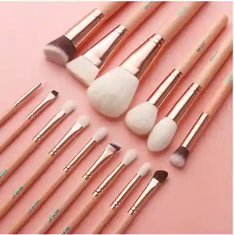 Makeup brushes with rose gold and white handles on a pink background