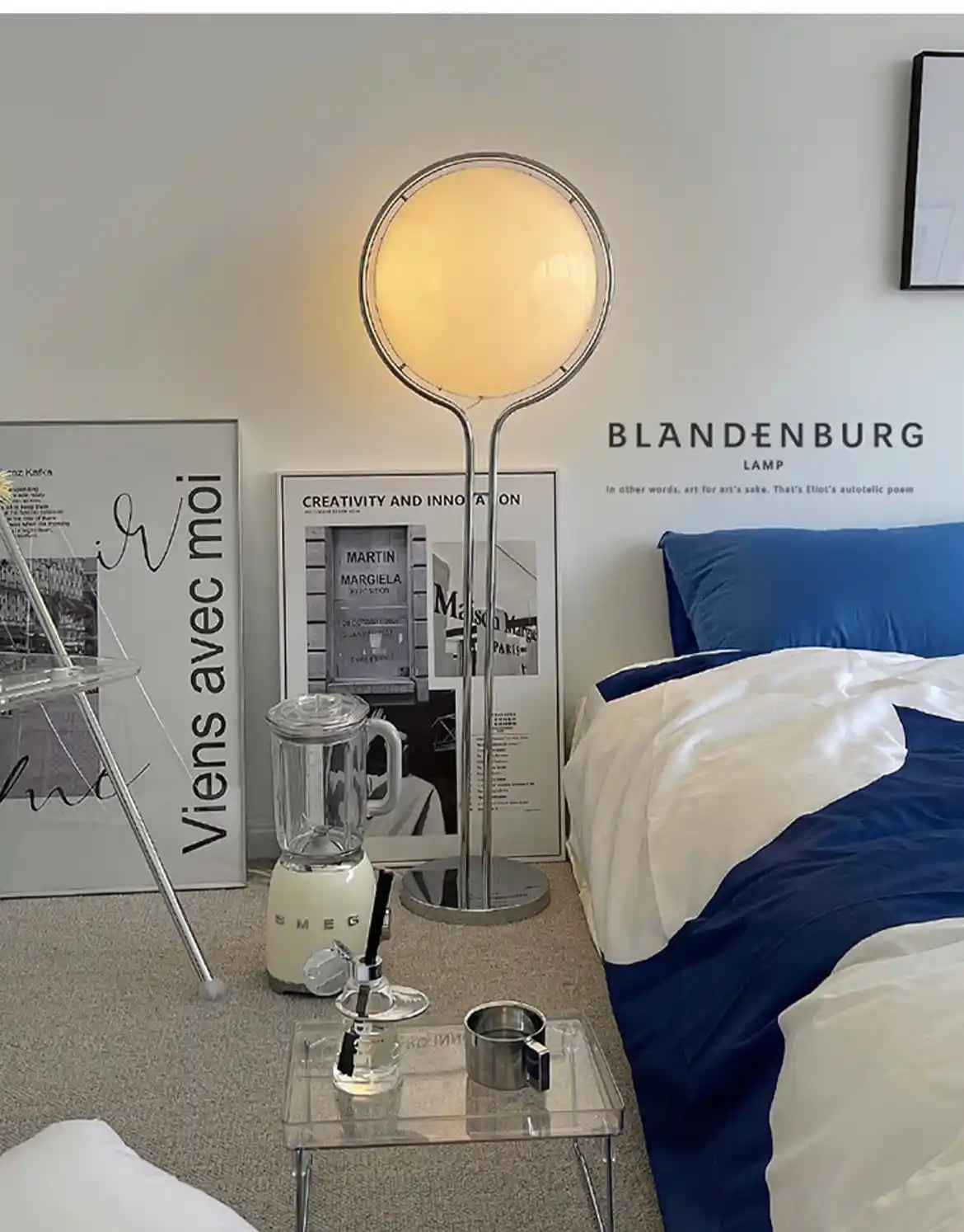 Modern bedroom with a Blandenburg lamp, bed, and small table.