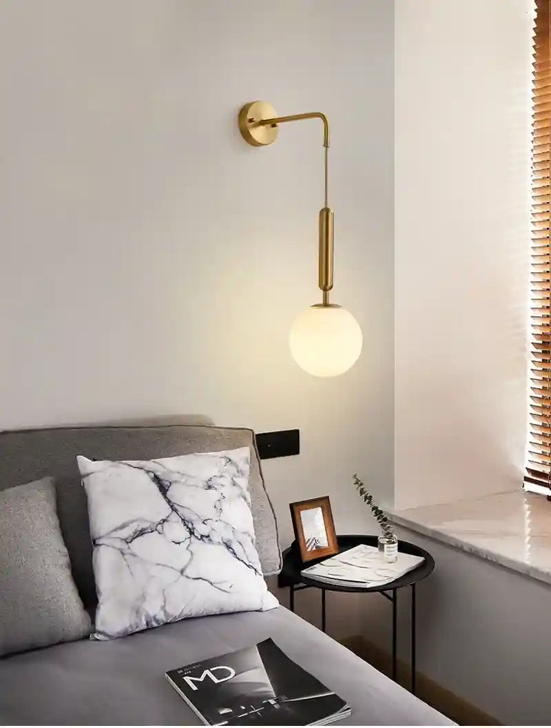 Modern bedroom with gold wall lamp, marble pillow, and side table.