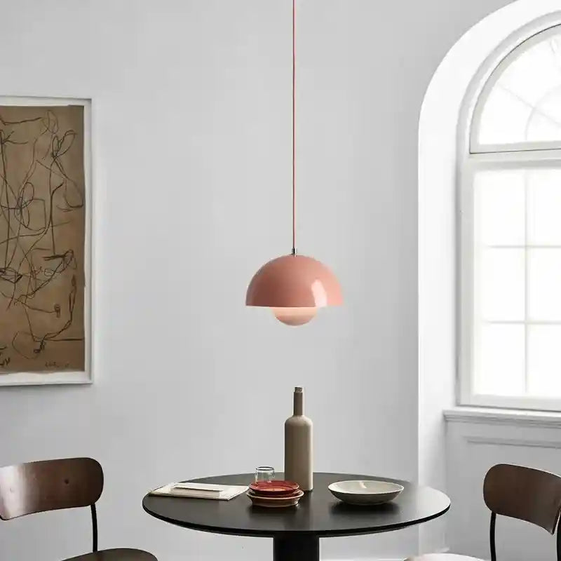 Modern dining room with a pink pendant light, round table, and chairs.