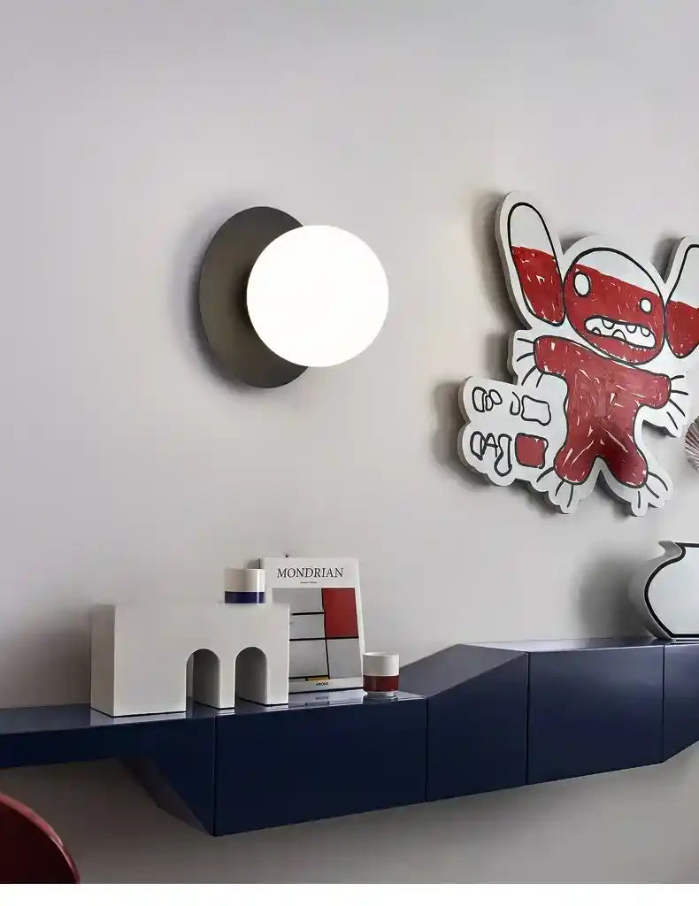 Modern interior design with a wall lamp, books, and a colorful wall art piece.