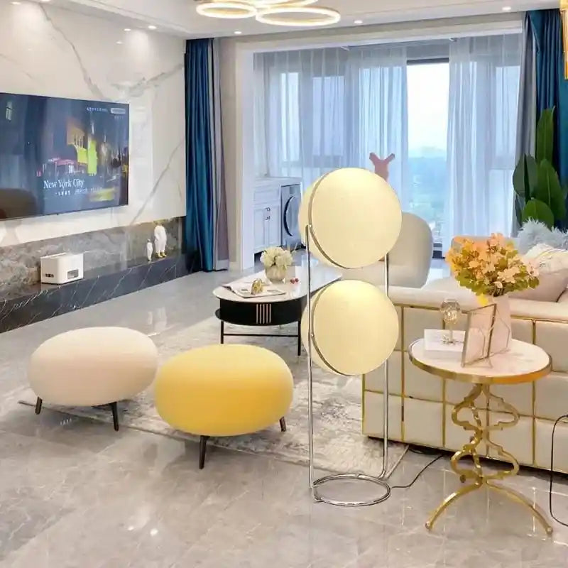 Modern living room with a floor lamp, ottomans, and a television.