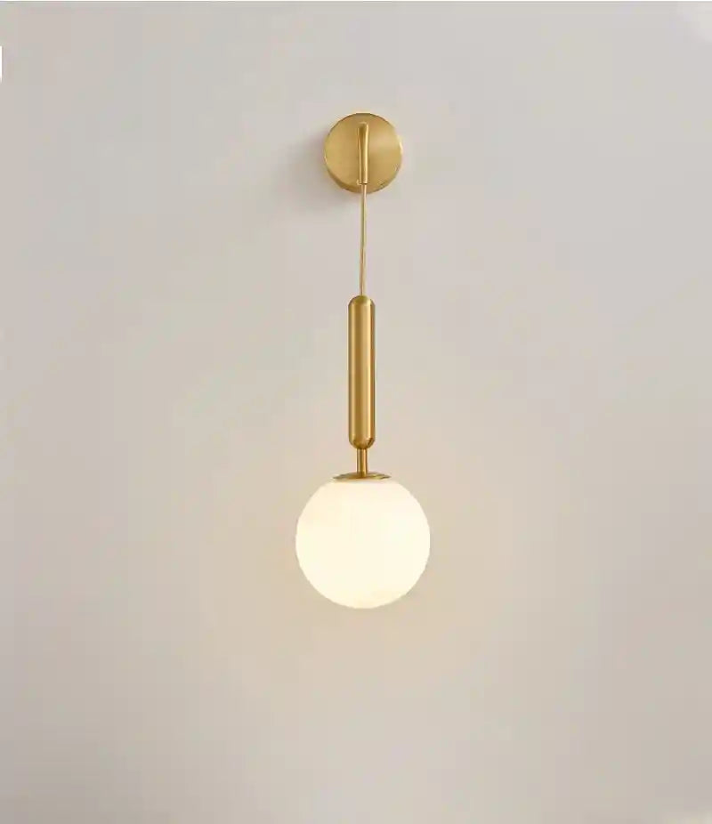 Modern pendant light with gold fixture and white glass shade on a plain background