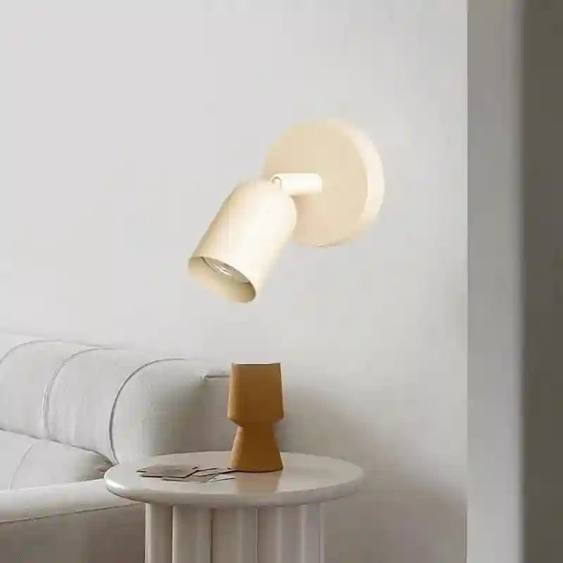 Modern wall lamp on a white wall with a small table and decorative item below.