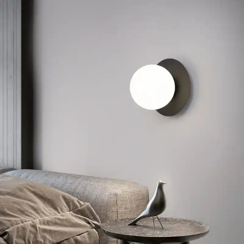 Modern wall light fixture on a gray wall with a sofa and decorative object in the foreground.