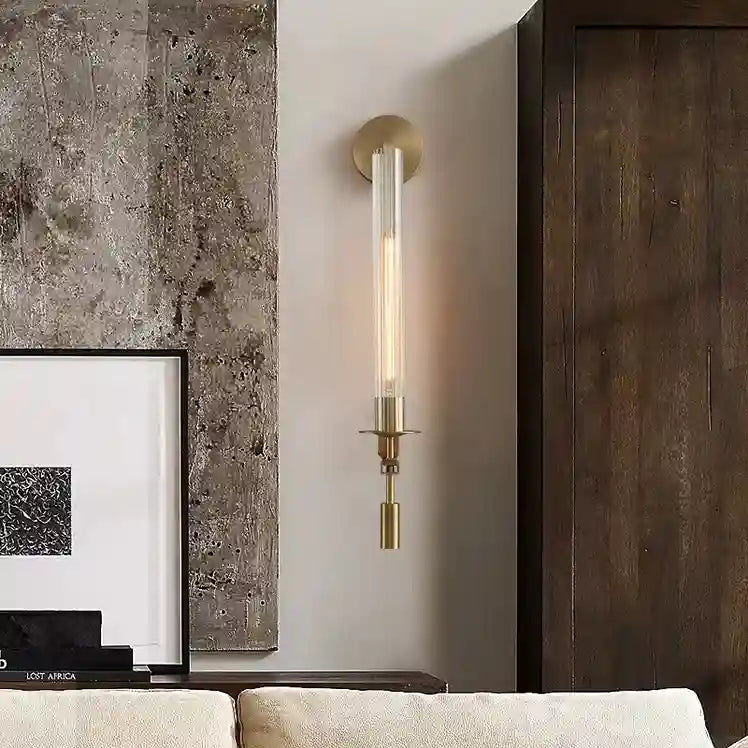 Modern wall sconce on a neutral wall with a framed picture and textured wall in the background.