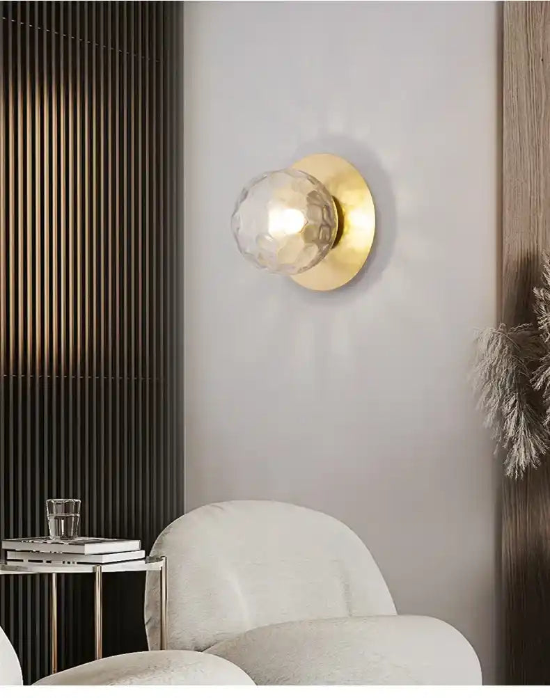Modern wall sconce with gold finish and clear glass shade in a stylish interior setting.