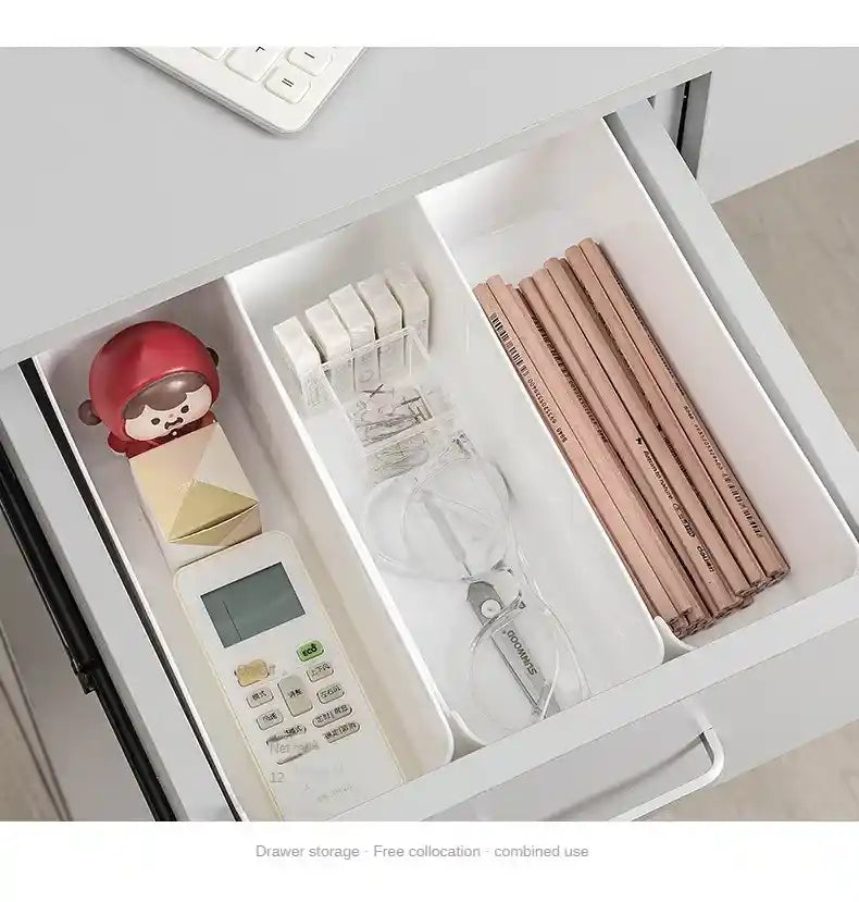 Open drawer with stationery items including pencils, a remote control, and a small figurine.