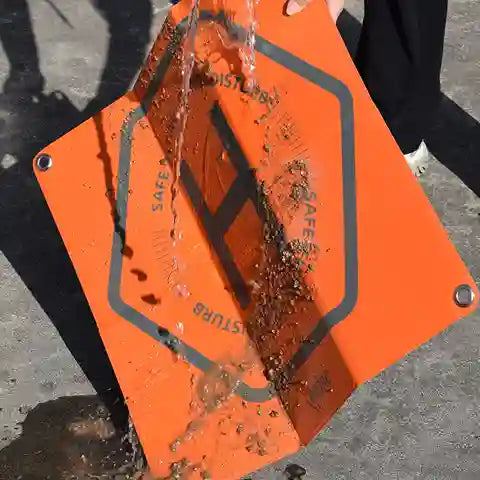 Orange safety mat with water splashing on it, showing its water-resistant properties.