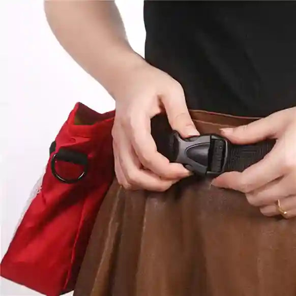 Person securing a black strap on a brown bag with a red item in the background