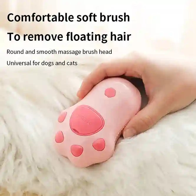 Pink pet grooming brush with paw design held by a hand on a fluffy white surface.