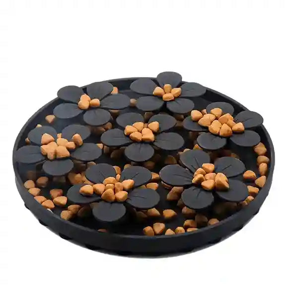 Round black tray with black and orange flower-shaped objects on a white background