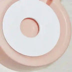 Close-up of a pink and white circular object with a central raised area.