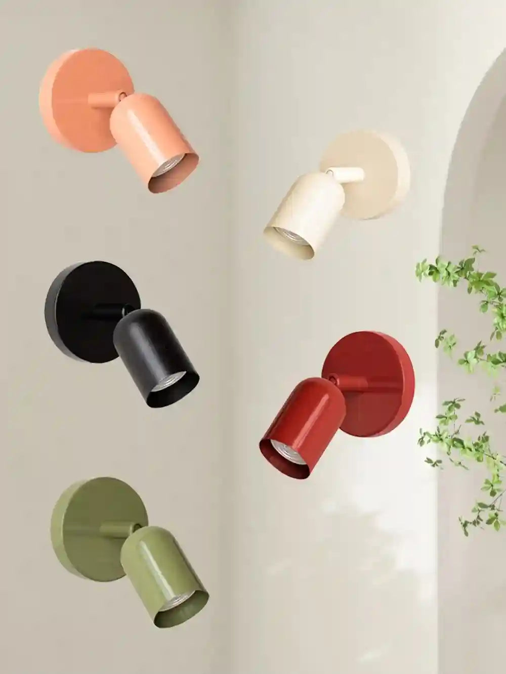 Set of colorful wall lights on a light gray wall with a plant in the corner.