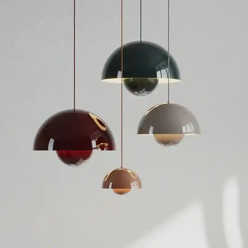 Set of four pendant lights with different colored glass shades on a plain background