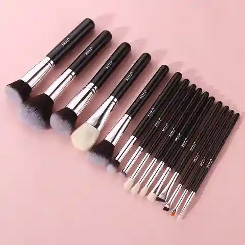 Set of makeup brushes with black handles on a pink background