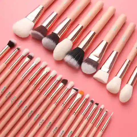 Set of makeup brushes with pink handles on a pink background