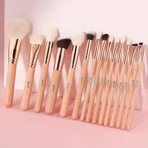 Set of makeup brushes with rose gold accents on a pink background