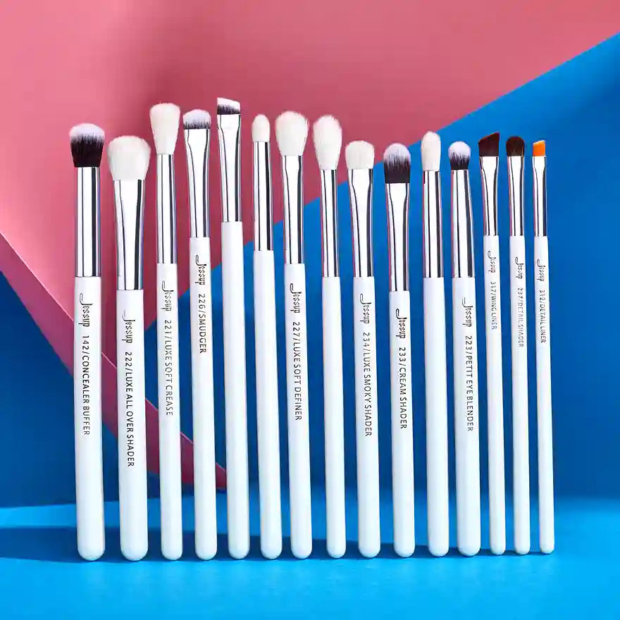 Set of makeup brushes with white handles and silver ferrules on a blue and pink background
