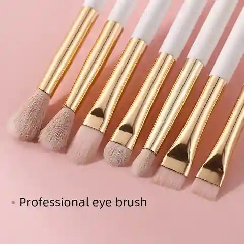 Set of professional eye brushes with gold and white handles on a pink background