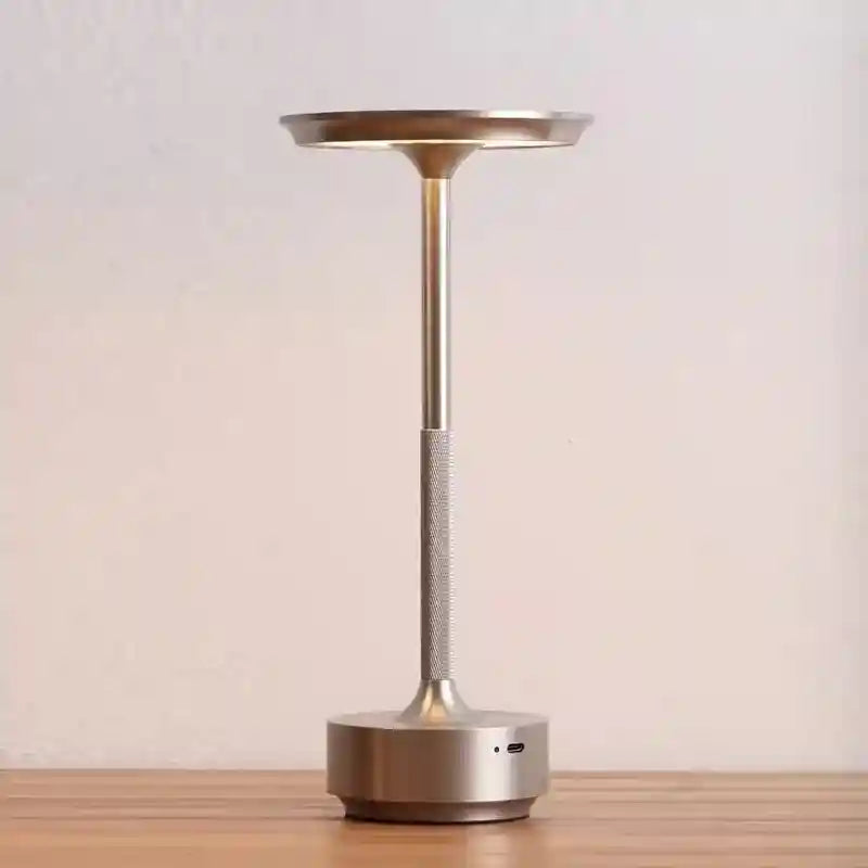 Silver lamp with a cylindrical base on a wooden surface and light background