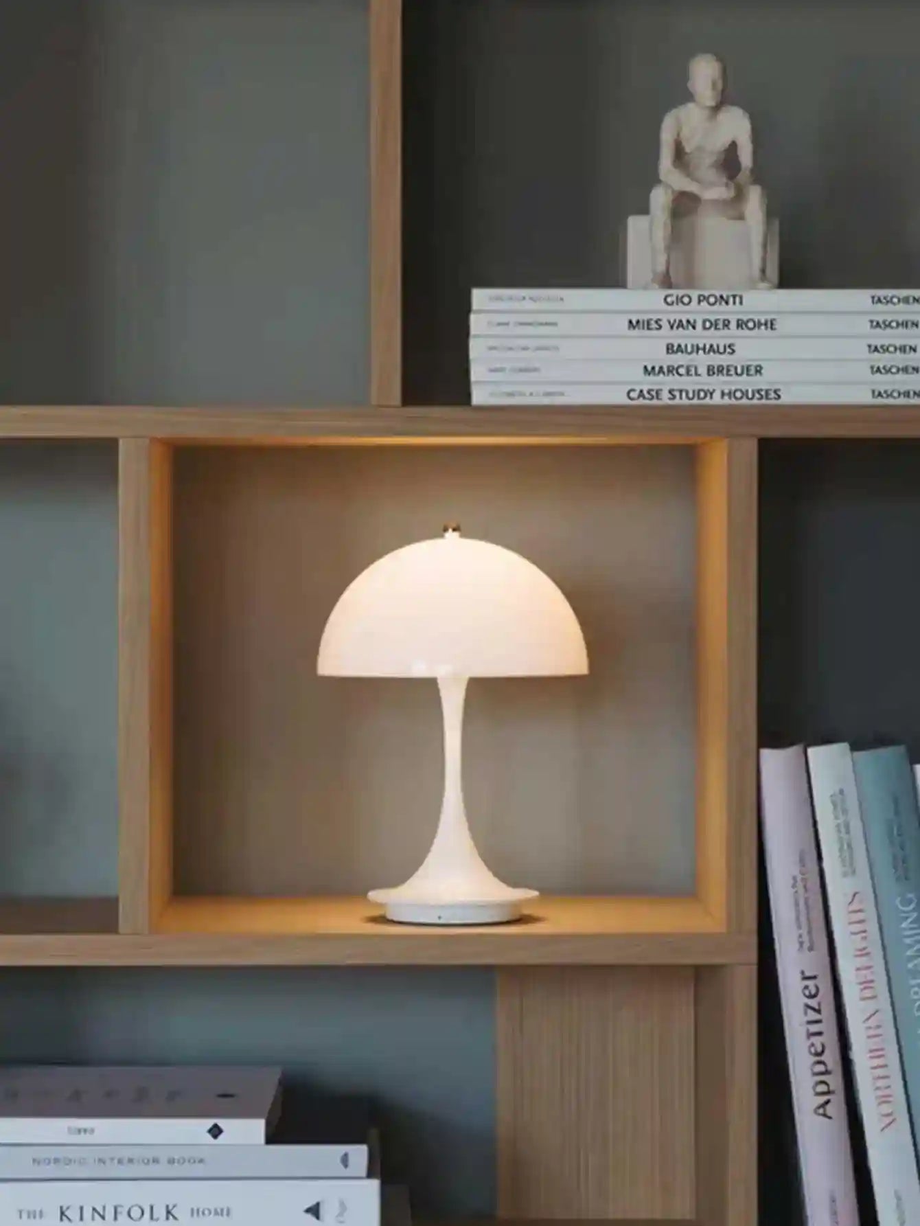 Small table lamp on a wooden shelf with books in the background