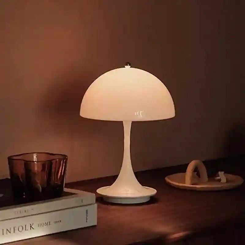 Table lamp on a wooden surface with books and a candle in the background