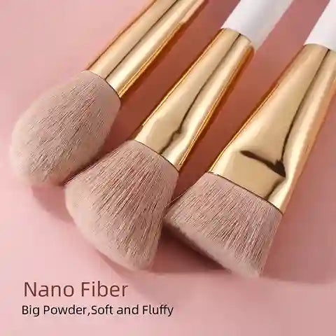 Three makeup brushes with gold handles and soft bristles on a pink background.