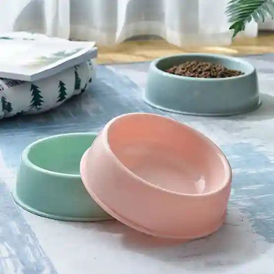 Two ceramic bowls, one green and one pink, on a marble surface with a blurred background.
